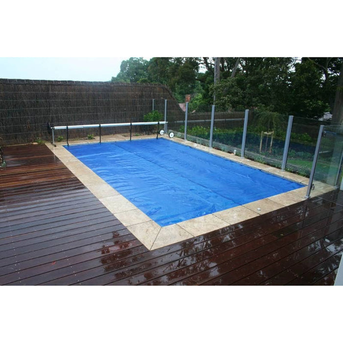 Blue solar bubble cover fitted across an outdoor swimming pool