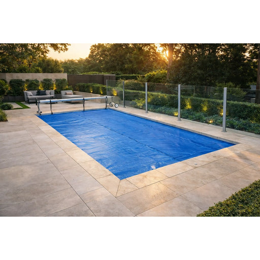 Blue solar swimming pool cover spread across a rectangular pool with roller at one end