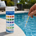 5-in-1 pool and spa test strips beside a pool, with a test strip held above the water