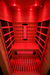 Interior of a 1 person infrared sauna with natural wood walls, black heater panels and red light therapy illumination
