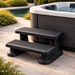 Black two-step spa steps beside a luxury spa pool on premium outdoor paving