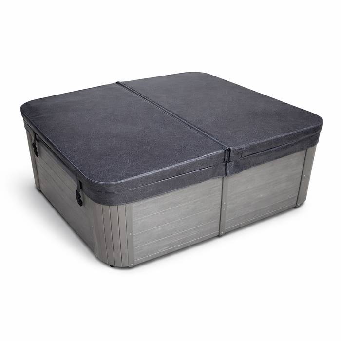 Charcoal grey square spa pool cover shown in angled view, with centre hinge, tapered insulated design and securing straps visible.