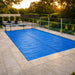 Blue solar bubble pool cover spread across an outdoor swimming pool
