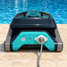 Rear view of the Dolphin Liberty 200 pool cleaner with its charging connector attached beside a swimming pool.