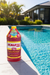 Scaletec Plus pool descaler and stain remover bottle beside a swimming pool